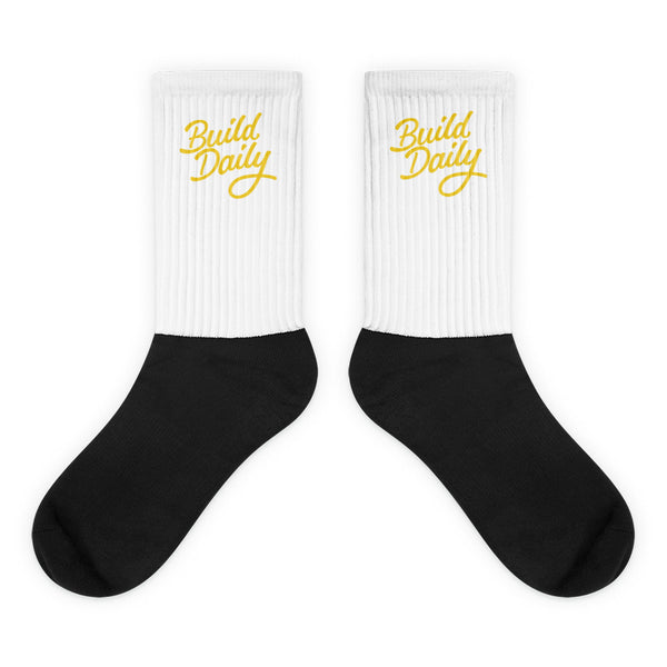 White and black socks with yellow build daily signature logo