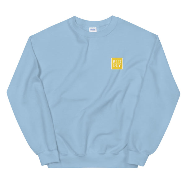 Light blue crewneck sweatshirt with yellow and white build daily monogram logo