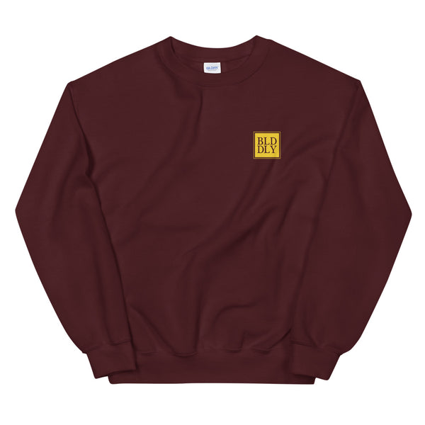 Maroon crewneck sweatshirt with yellow build daily monogram logo